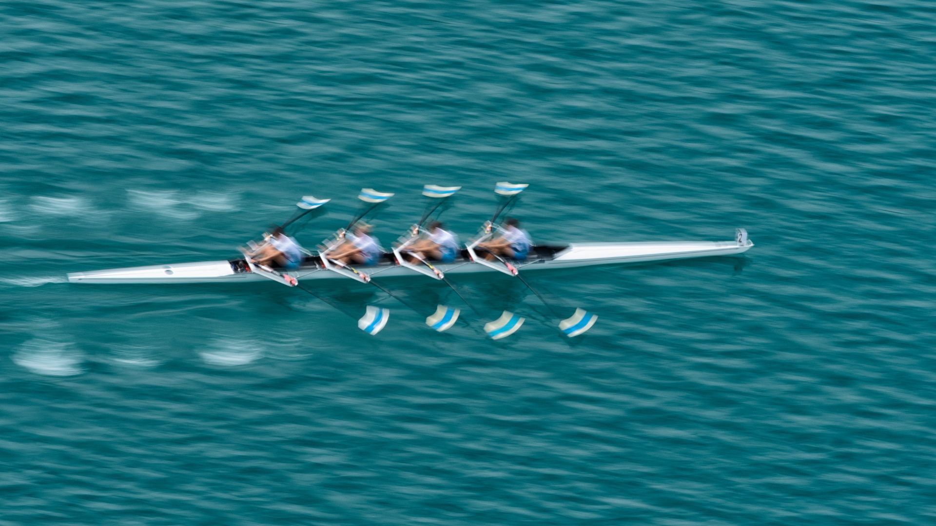 upper vie of quadruple scull rowing team on the water, blurred motion